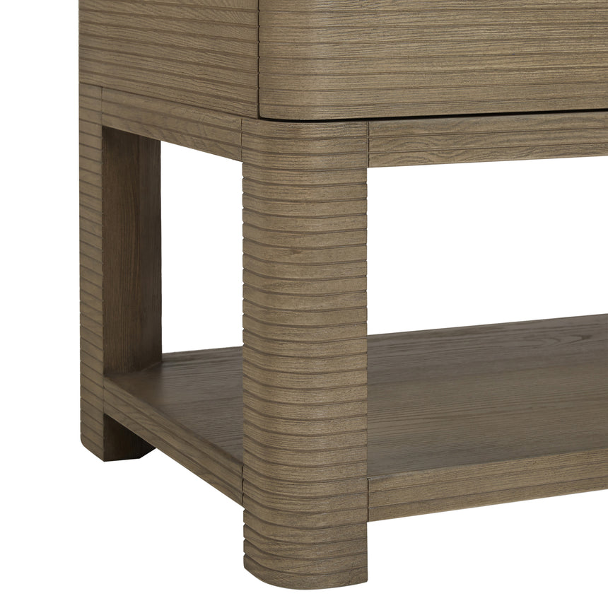 A modern bathroom vanity with a light oak wood frame, six drawers, an open lower shelf, and a white marble top with an integrated sink. The vanity is styled in a bright bathroom with a white freestanding tub, a gold faucet, and a glass shower stall in the background.