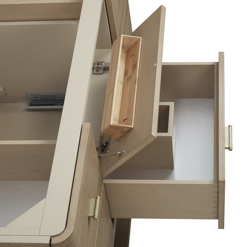 A modern bathroom vanity with a light oak wood frame, six drawers, an open lower shelf, and a white marble top with an integrated sink. The vanity is styled in a bright bathroom with a white freestanding tub, a gold faucet, and a glass shower stall in the background.