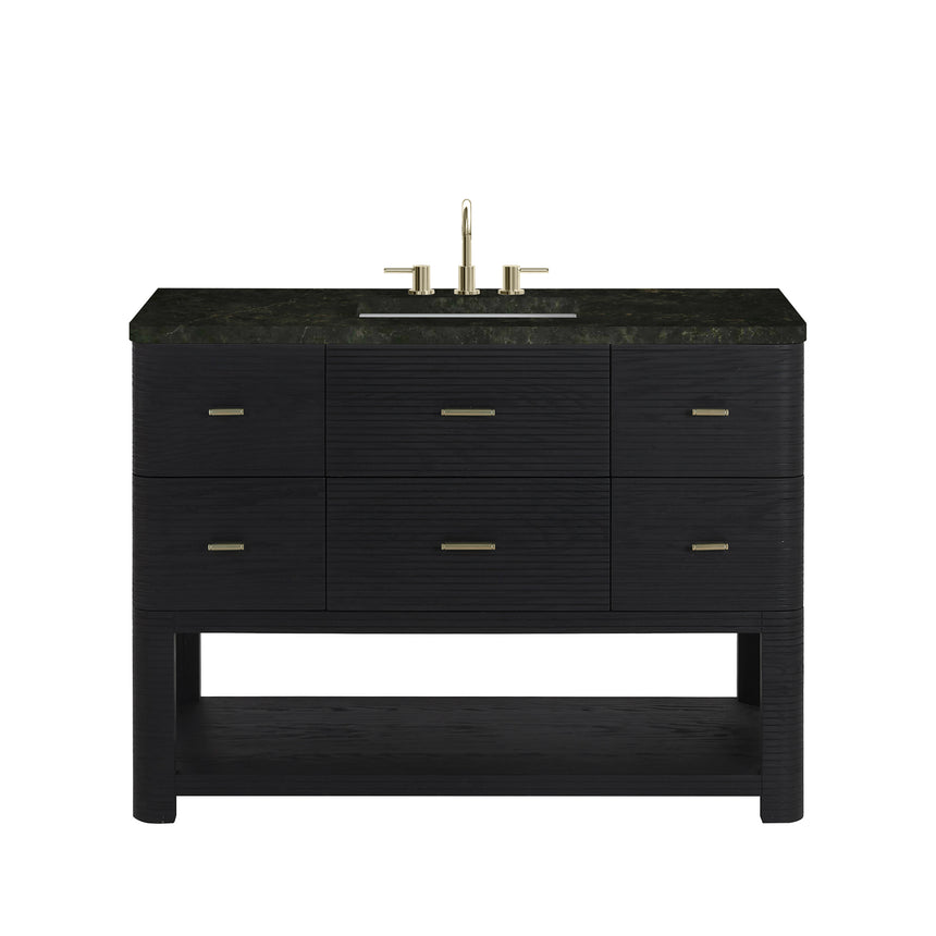 A modern bathroom vanity with a light oak wood frame, six drawers, an open lower shelf, and a white marble top with an integrated sink. The vanity is styled in a bright bathroom with a white freestanding tub, a gold faucet, and a glass shower stall in the background.