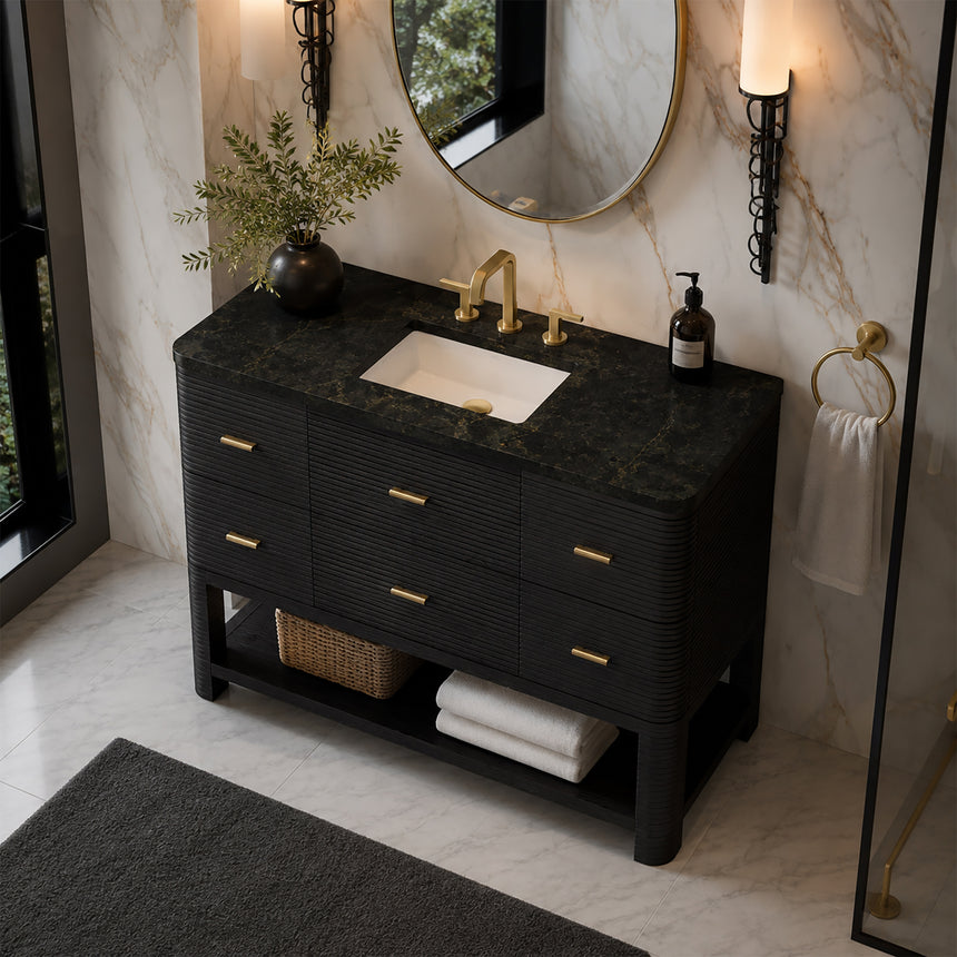 A modern bathroom vanity with a light oak wood frame, six drawers, an open lower shelf, and a white marble top with an integrated sink. The vanity is styled in a bright bathroom with a white freestanding tub, a gold faucet, and a glass shower stall in the background.