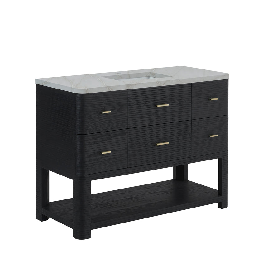 A modern bathroom vanity with a light oak wood frame, six drawers, an open lower shelf, and a white marble top with an integrated sink. The vanity is styled in a bright bathroom with a white freestanding tub, a gold faucet, and a glass shower stall in the background.