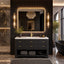 A modern bathroom vanity setup in a luxurious black wood bathroom, featuring a black ribbed vanity cabinet with a white countertop, gold handles, and an integrated sink. A large rectangular mirror with a warm LED light border is mounted on a black slatted wall, flanked by vertical gold sconces.