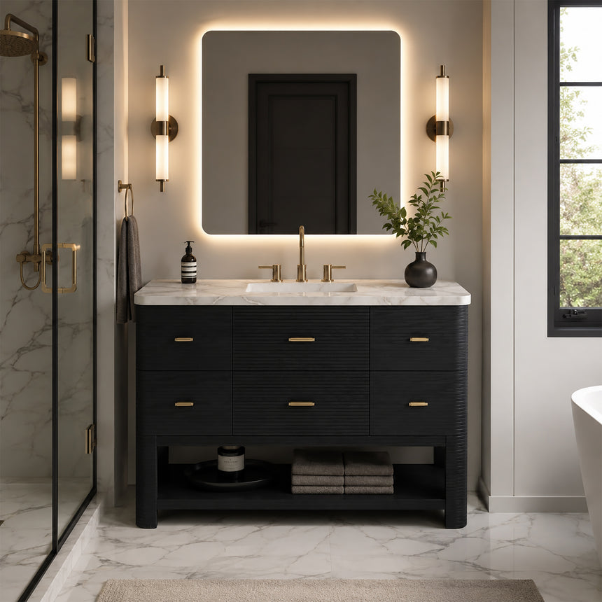 A modern bathroom vanity with a light oak wood frame, six drawers, an open lower shelf, and a white marble top with an integrated sink. The vanity is styled in a bright bathroom with a white freestanding tub, a gold faucet, and a glass shower stall in the background.