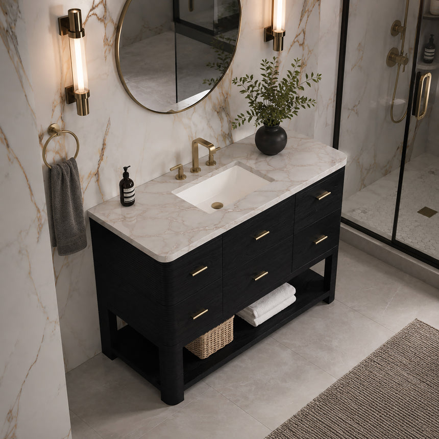 A modern bathroom vanity with a light oak wood frame, six drawers, an open lower shelf, and a white marble top with an integrated sink. The vanity is styled in a bright bathroom with a white freestanding tub, a gold faucet, and a glass shower stall in the background.