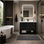 A modern bathroom interior featuring a black vanity cabinet with a white countertop and sink, a large backlit rectangular mirror, a freestanding white bathtub, and a glass shower enclosure.