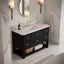A modern bathroom vanity with a black textured cabinet, white countertop, and gold faucet and handles, shown in a marble bathroom setting.