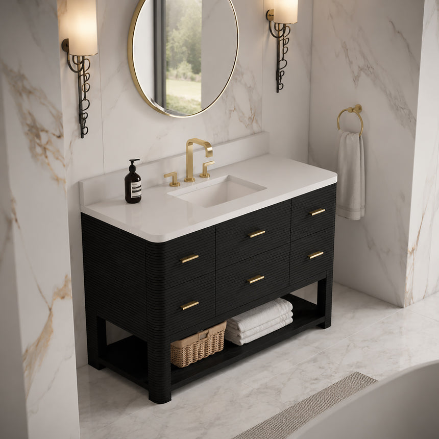 A modern bathroom vanity with a light oak wood frame, six drawers, an open lower shelf, and a white marble top with an integrated sink. The vanity is styled in a bright bathroom with a white freestanding tub, a gold faucet, and a glass shower stall in the background.
