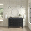 Bathroom with a black vanity, round mirror, and decorative elements.
