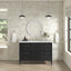 Bathroom with a black vanity, round mirror, and decorative elements.