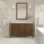 Bathroom vanity with wooden cabinet, mirror, and decorative elements.