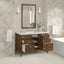 Bathroom vanity with open drawers, mirror, and decorative elements against a patterned wall.