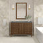 Bathroom vanity with mirror, lights, and decorative elements against a patterned wall.
