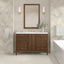 Bathroom vanity with wooden cabinet, mirror, and decorative elements against a patterned wall.