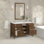 Bathroom vanity with open drawers, mirror, and decorative elements against a patterned wall.