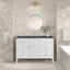 Bathroom vanity with round mirror, sink, and decorative elements against a patterned wall.