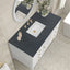 Bathroom vanity with black countertop, white sink, and gold fixtures.