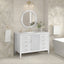 Bathroom with white vanity, round mirror, and bathtub against a tiled wall.
