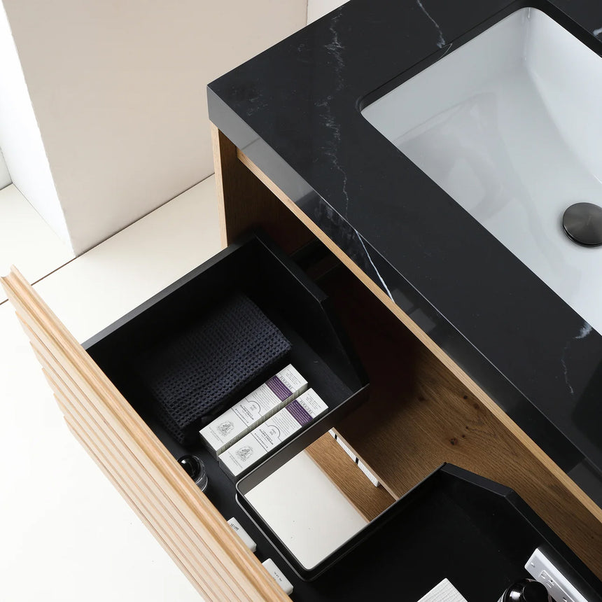 A modern floating bathroom vanity with a light oak wood finish, a white countertop, and an integrated sink, shown in a styled bathroom setting with a bathtub, shower glass, and decorative plants.