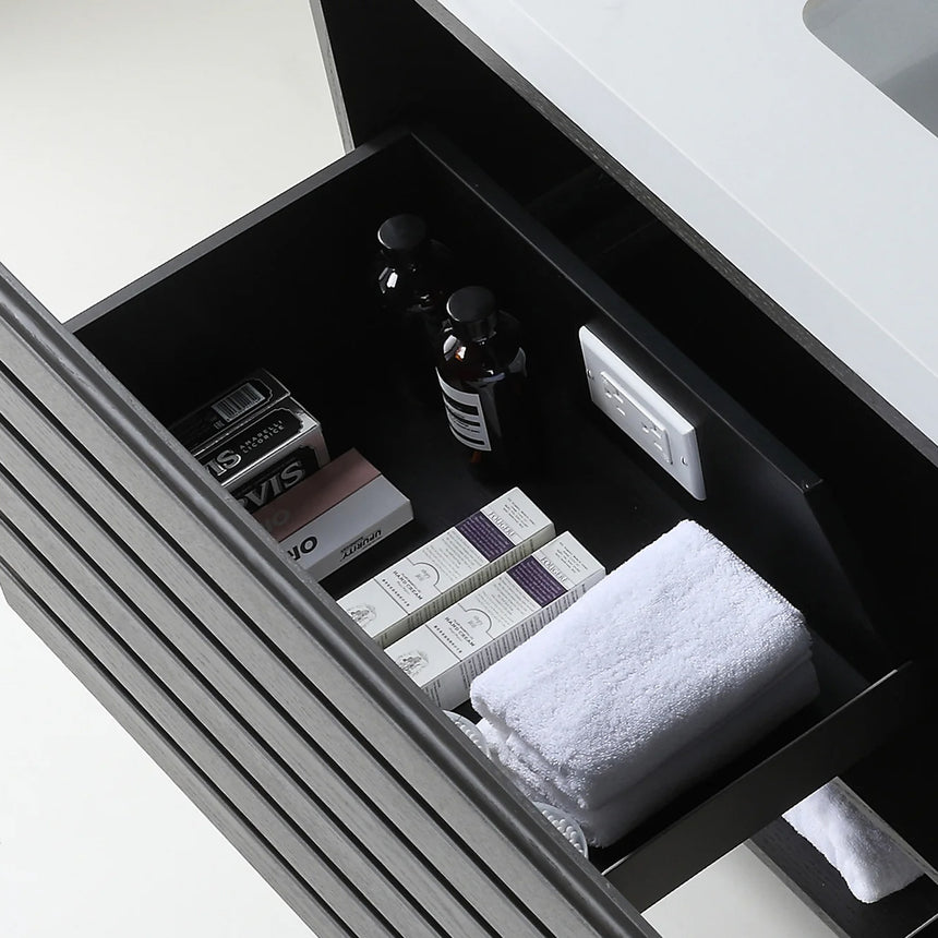 A modern floating bathroom vanity with a light oak wood finish, a white countertop, and an integrated sink, shown in a styled bathroom setting with a bathtub, shower glass, and decorative plants.