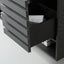Close-up of a dark charcoal gray wooden drawer with horizontal grooves, partially pulled open to reveal a light gray textured cloth inside.