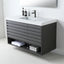 A modern wall-mounted bathroom vanity with a dark gray wood-grain cabinet, a white countertop, an integrated rectangular sink, and a black faucet. The cabinet has multiple horizontal drawer fronts and an open lower shelf with folded towels and storage cubes, set against a clean white wall.