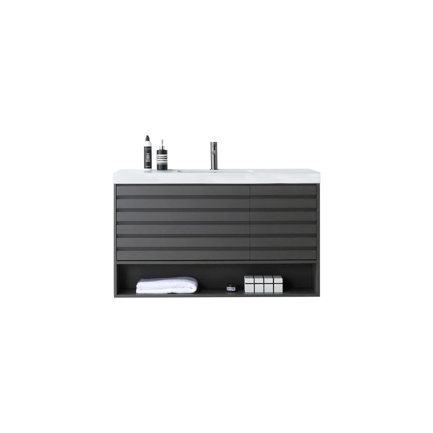 A modern floating bathroom vanity with a light oak wood finish, a white countertop, and an integrated sink, shown in a styled bathroom setting with a bathtub, shower glass, and decorative plants.