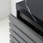 Close-up of a modern cabinet or dresser with dark gray slatted drawer fronts and a glossy black top featuring a white marble vein.