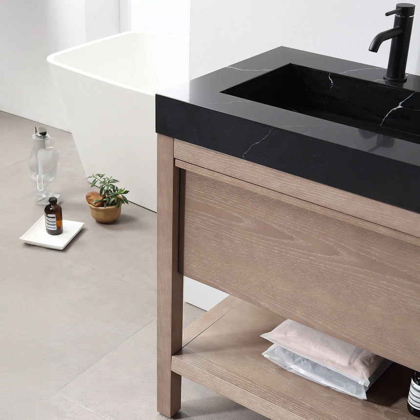 Bathroom vanity with black countertop and wooden cabinet in a bright room.