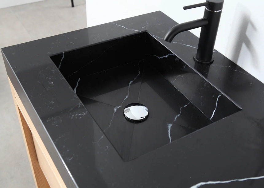 Bathroom vanity with black countertop and wooden cabinet in a bright room.