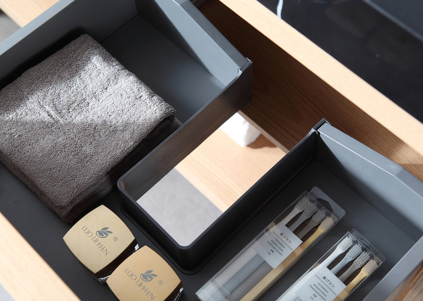 Bathroom vanity with black countertop and wooden cabinet in a bright room.