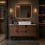 Modern bathroom vanity with wooden cabinet, mirror, and lighting fixtures.