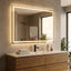 Bathroom vanity with a large illuminated mirror, sink, and wooden cabinets.