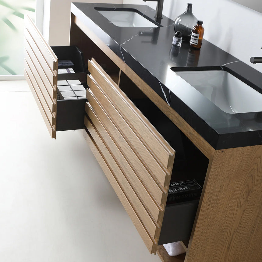 A modern floating bathroom vanity with a light oak wood finish, a white countertop, and an integrated sink, shown in a styled bathroom setting with a bathtub, shower glass, and decorative plants.