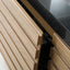 Close-up of a light oak wood kitchen cabinet with a modern black stone countertop, showing the drawer front details and wood grain.