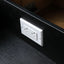 A white double electrical outlet cover plate mounted on the front of a black wooden drawer or cabinet interior.