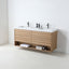 A modern floating bathroom vanity with a light oak wood frame, a white double sink countertop, and two matte black faucets, shown against a clean white wall and floor.