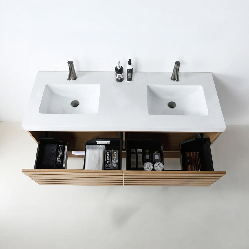 A modern floating bathroom vanity with a light oak wood finish, a white countertop, and an integrated sink, shown in a styled bathroom setting with a bathtub, shower glass, and decorative plants.