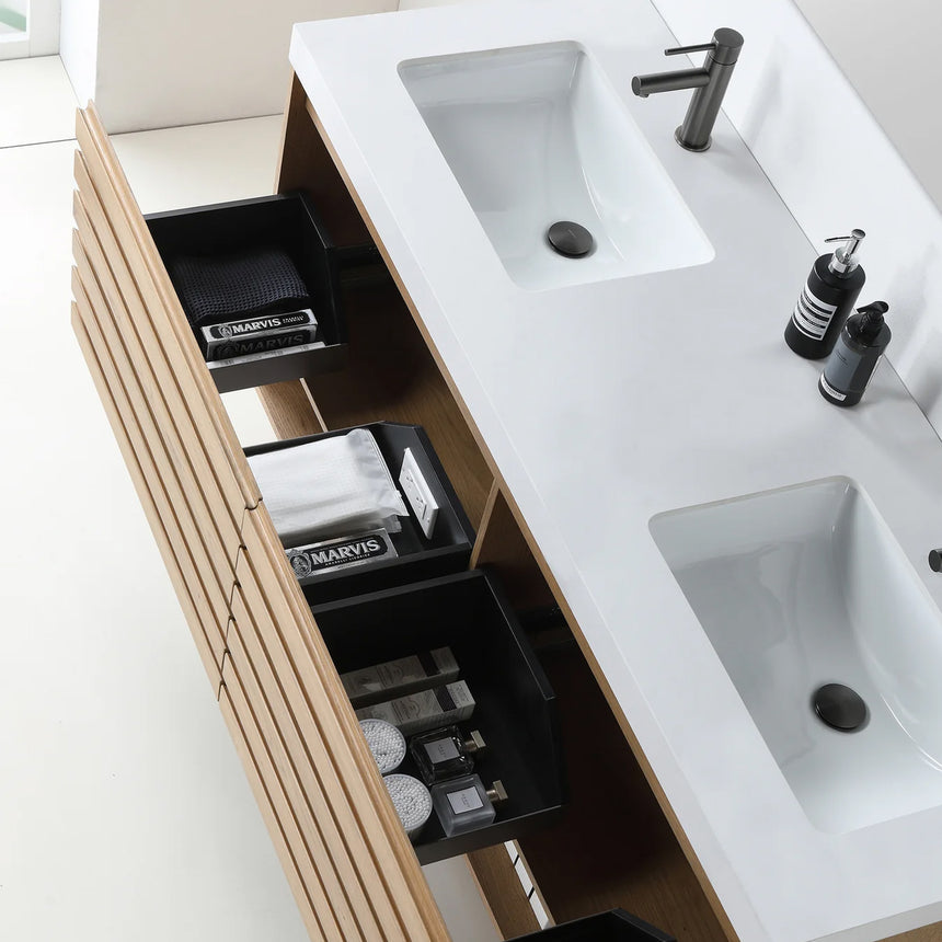 A modern floating bathroom vanity with a light oak wood finish, a white countertop, and an integrated sink, shown in a styled bathroom setting with a bathtub, shower glass, and decorative plants.