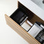 A wooden drawer organizer tray holding black and white boxed items, shown inside an open drawer next to a white countertop. The brand name MARVIS is visible on the boxes.