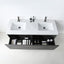 A modern wall-mounted bathroom vanity with a white double basin countertop, black cabinet base, and two matte black faucets. The lower drawer is open, showing storage compartments with toiletries, against a clean white wall and floor.