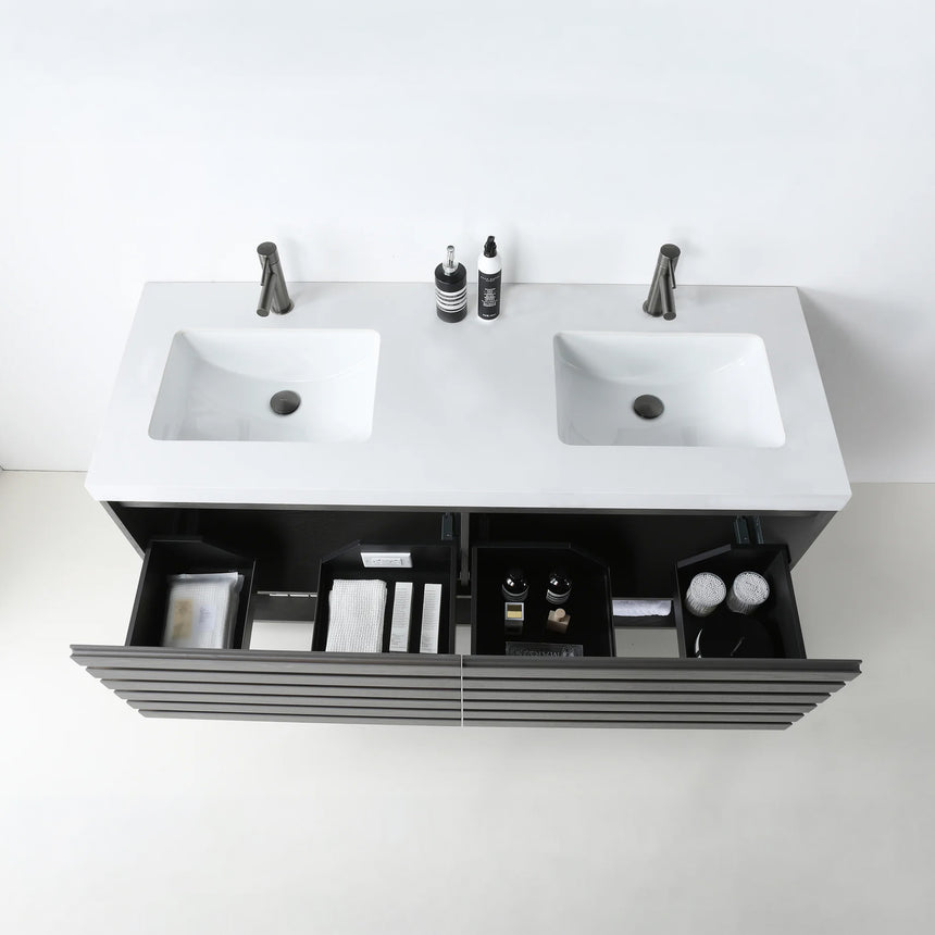 A modern floating bathroom vanity with a light oak wood finish, a white countertop, and an integrated sink, shown in a styled bathroom setting with a bathtub, shower glass, and decorative plants.