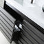 A modern dark gray bathroom vanity with a white countertop and sink, showing an open drawer with a black pull handle and a small storage compartment.
