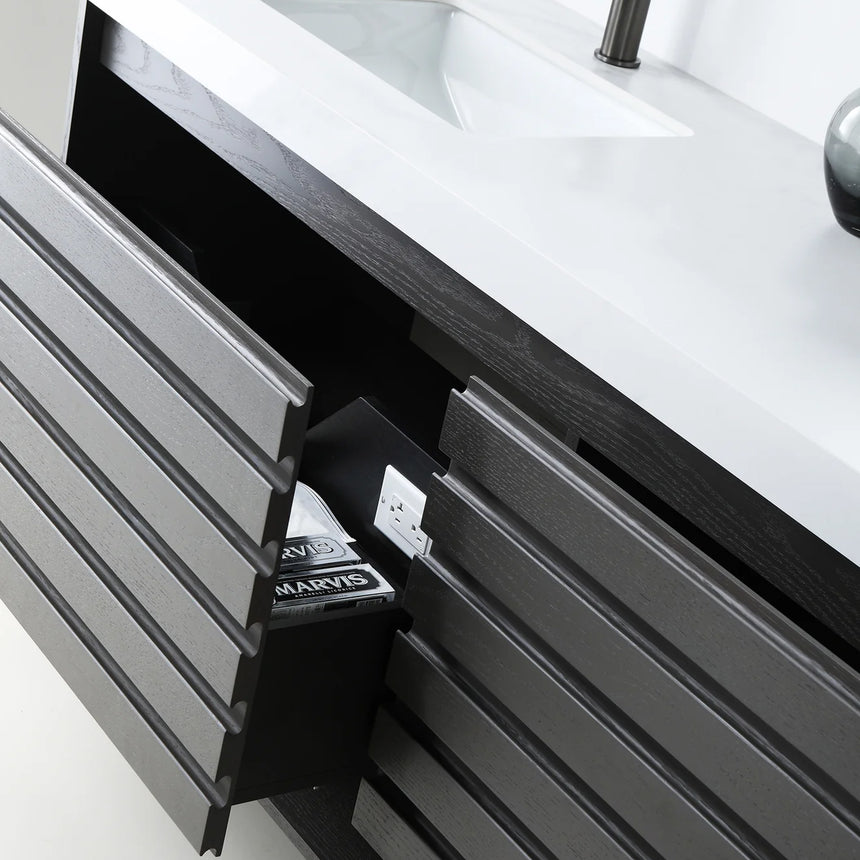 A modern floating bathroom vanity with a light oak wood finish, a white countertop, and an integrated sink, shown in a styled bathroom setting with a bathtub, shower glass, and decorative plants.
