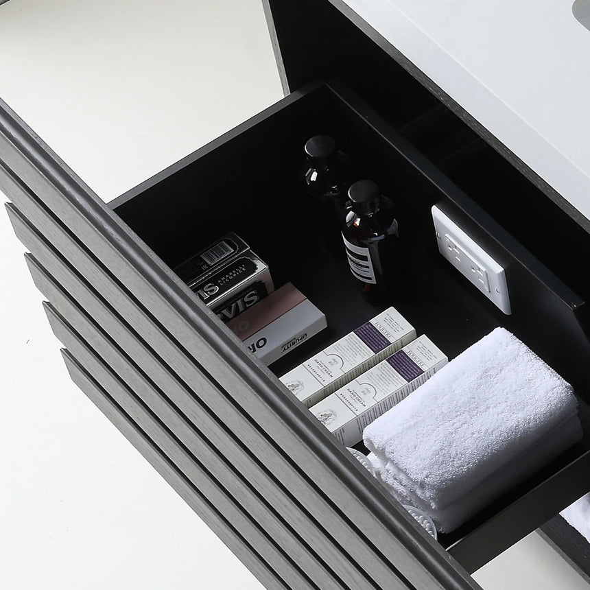 A modern floating bathroom vanity with a light oak wood finish, a white countertop, and an integrated sink, shown in a styled bathroom setting with a bathtub, shower glass, and decorative plants.