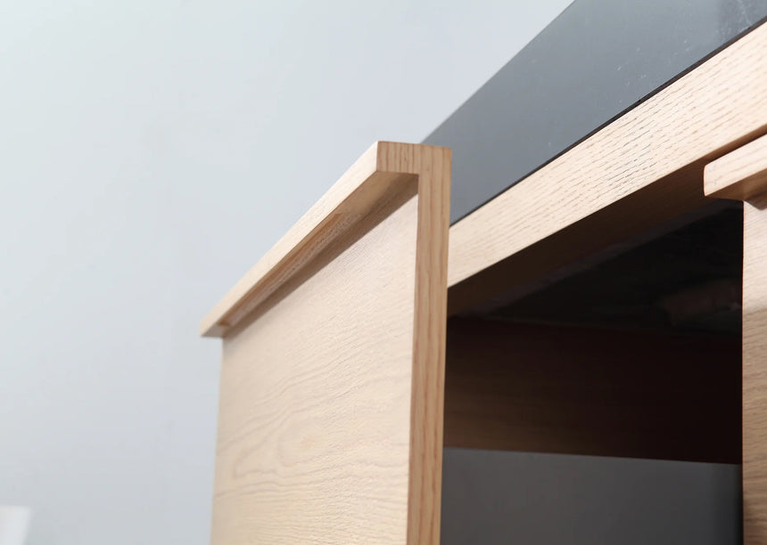 Bathroom vanity with black countertop and wooden cabinet in a bright room.