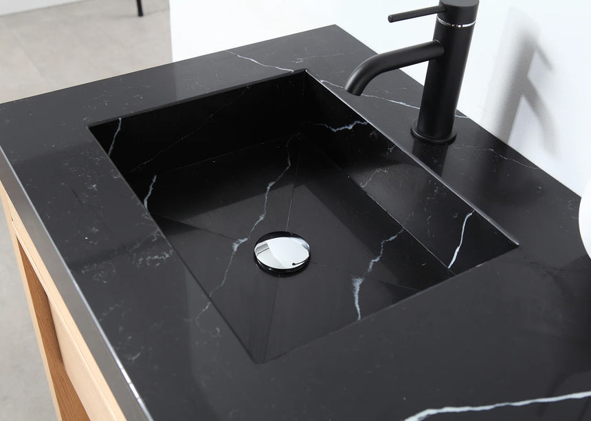 Bathroom vanity with black countertop and wooden cabinet in a bright room.