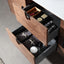 Open wooden drawer with various items including bottles and a box on a light gray floor.