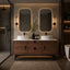 Modern bathroom with wooden vanity, double sinks, and illuminated mirrors.
