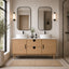 Bathroom with wooden vanity, two mirrors, and a plant.