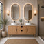 Bathroom vanity with two oval mirrors, lights, and decor.
